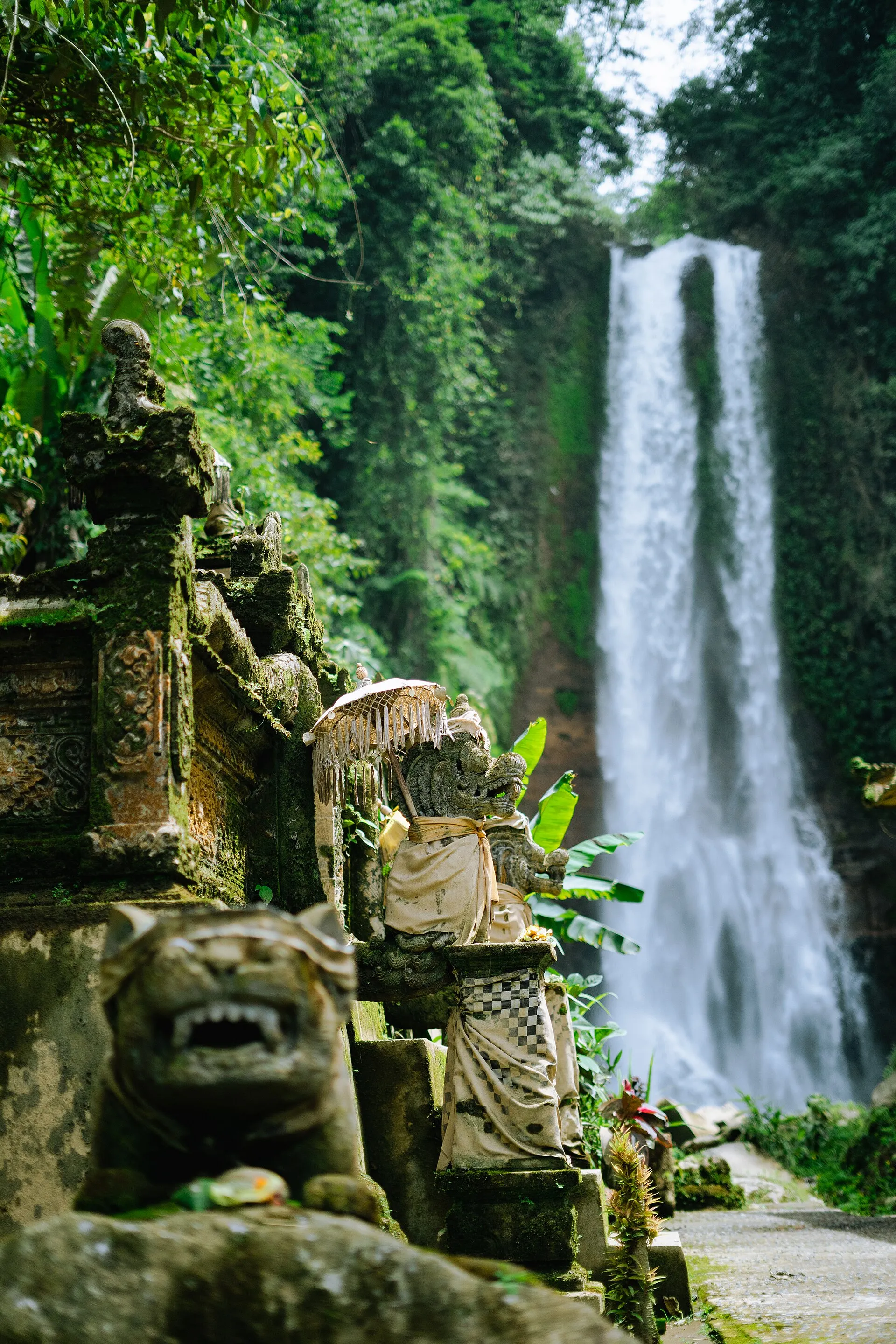 Gitgit Waterfall, Buleleng Bali - tall falls with temple statues on path